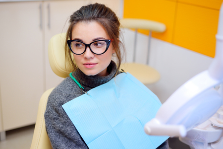 cute young woman with glasses in dental chairの写真素材
