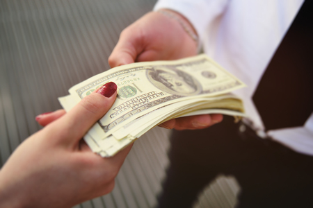 woman gives a man a pack of American dollarsの写真素材