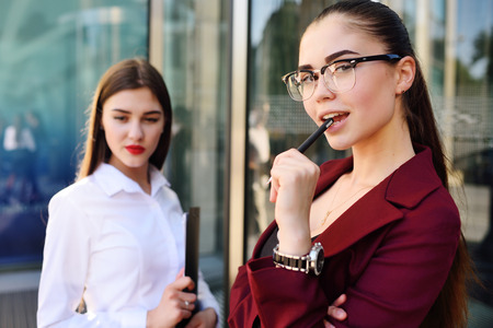 two young pretty business women against a modern glass office buildingの写真素材