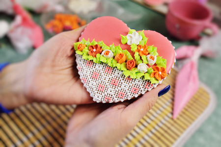 woman confectioner decorates and decorates the glaze with gingerbread cookies in the shape of heart. Valentines Day, February 14, symbol, valentine, gift.の写真素材