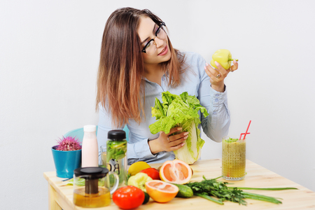 beautiful young girl with glasses with Peking cabbage and pepper in hands on the background of a table with vegetables. Healthy Eating, Weight Loss, Diet, Vegetarianism, Nutrition, Lifestyleの写真素材