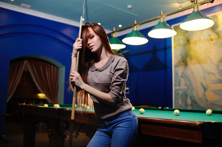 nice cute girl with a cue in her hands playing billiardsの写真素材
