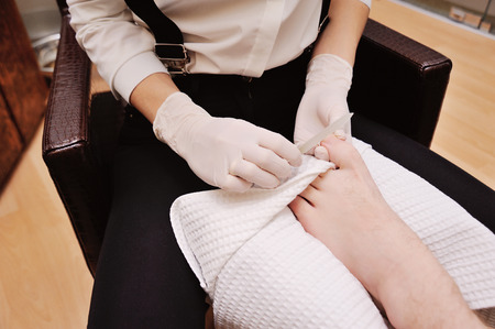 a young girl makes a man pedicure in the background of a beauty salon. Nail careの写真素材