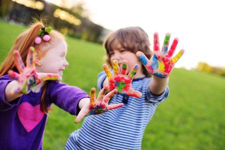 two young cheerful children show their hands stained with colorful paintsの写真素材