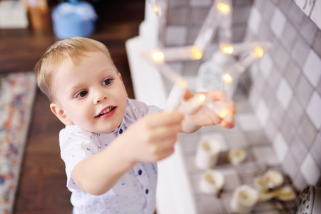 cute baby boy dresses up a christmas tree and smilesの写真素材