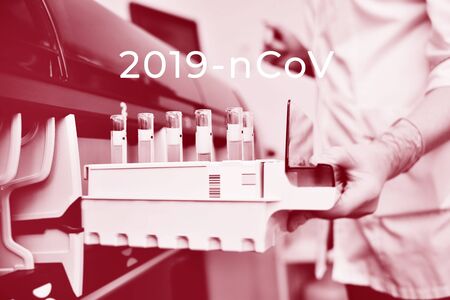A scientist in a laboratory places test tubes with blood or urine in the container of a thermal analyzer. Modern medical computerized equipmentの写真素材