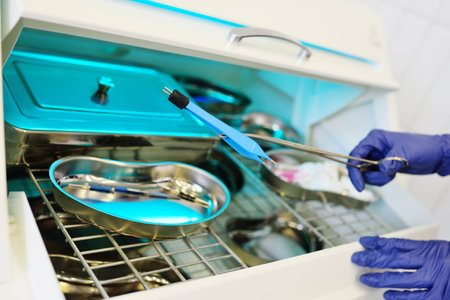 close-up of a doctors hands in blue rubber gloves taking sterile instruments out of an ultraviolet sterilizer.の写真素材