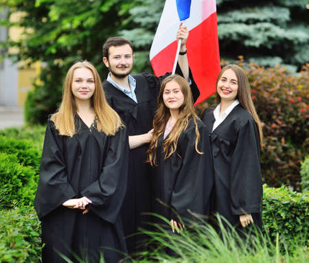 group of students graduates of the Faculty of Foreign Languages in robes hold the flag of France in their handsの写真素材