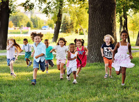 a group of preschoolers running on the grass in the Park.の写真素材