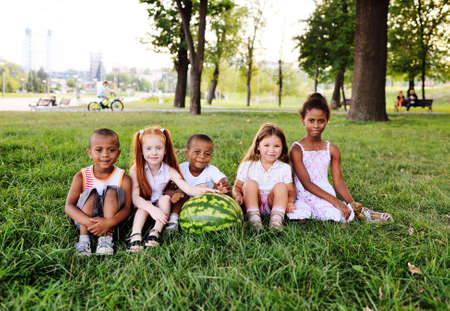 preschool children in the Park on the grass holding a huge watermelonの写真素材