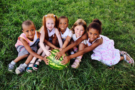 preschool children in the Park on the grass holding a huge watermelonの写真素材