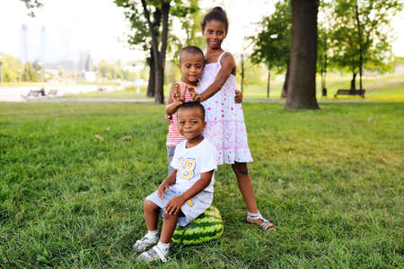 happy black African American kids playing with a big watermelon in the Park on the grass and smiling.の写真素材