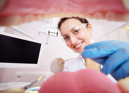 pretty young female dentist examines the patients teeth. View from inside the jaw.の写真素材
