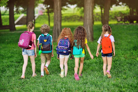 group of children with school backpacks walking hand in hand. Holidays, back to school, summer camp.の写真素材