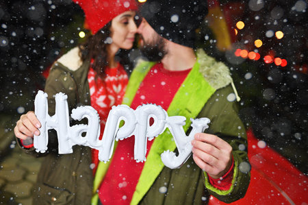 couple of lovers - a man and a woman kiss and hold in their hands the inscription happy on the...