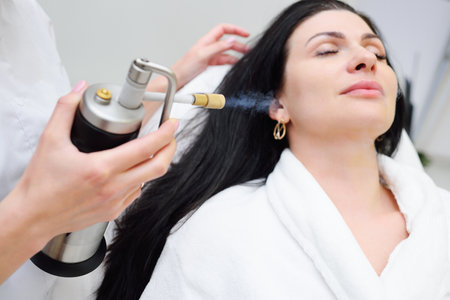 cosmetologist makes a cryomassage of the face to the patient â a cosmetological procedure of exposure to the skin with liquefied nitrogen using a cryodestructor apparatusの写真素材