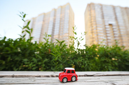 toy red car on the background of new buildings and greenery.の写真素材