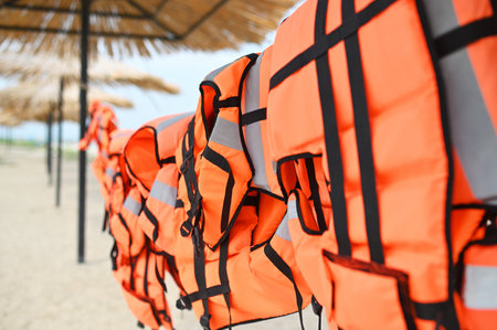lots of orange life jackets on the background of sand, sea and straw umbrellasの写真素材