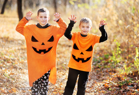 boys friends in orange costumes with a picture of pumpkin Jack scare against the backdrop of autumn...