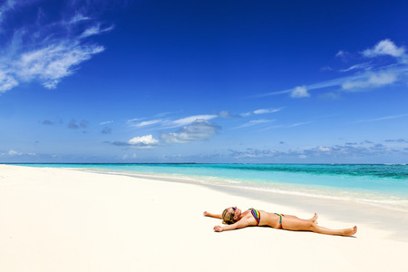 young woman lies on the shore of a tropical sea. on white sandの写真素材
