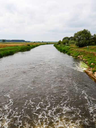 River in the countryside in summer with green grass and blue sky.の写真素材