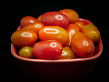 Cherry tomatoes in a bowl on a black background. Selective focus.の写真素材