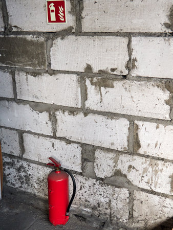 Fire extinguisher on the brick wall background, closeup of photoの写真素材