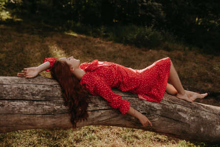high angle view portrait a young and beautiful woman in a red summer dress with white flecks resting...