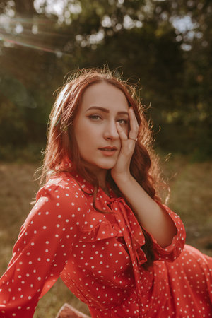 Redhead woman posing on a camera outdoor on the dry grass field on the forest backgroundの写真素材