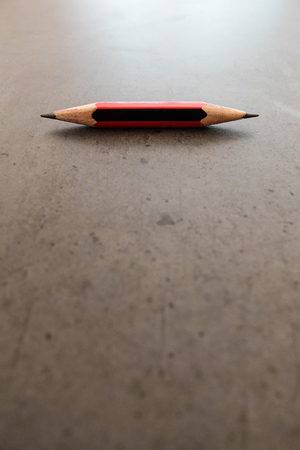 A small pencil, shapened at both ends, on a gray tableの写真素材