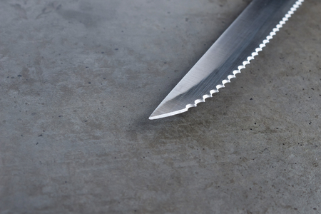Serrated knife on a dark gray tableの写真素材