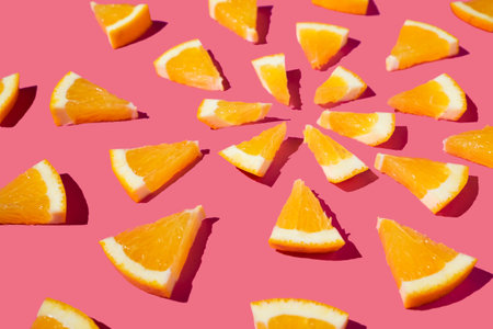 Mandala concept from triangle slices of orange fruit arrangement on bright pink background. High...