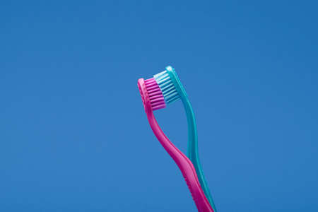 Pink and blue toothbrushes arranged like couple kissing for minimal concept idea on blue background conceptの写真素材