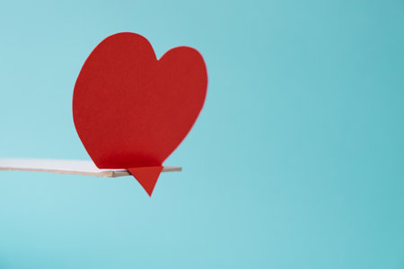 Sadness concept with red heart alone and bent over diving board on minimal aesthetic muted blue color backgroundの写真素材