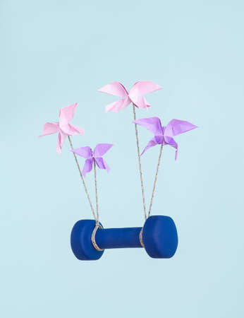 Origami butterflies in teamwork and success concept working to lift blue exercise weight. Pastel colors and positivity feeling.の写真素材