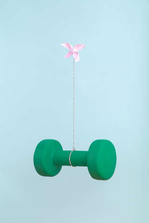 Solo pink origami butterfly working alone to light heavy burden of exercise weight. Minimal art...