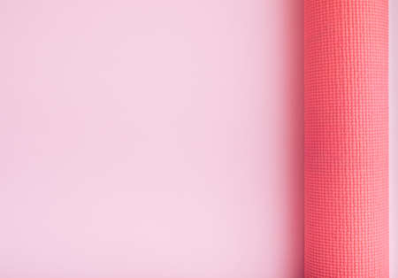 Monochrome fitness theme with pink yoga exercise mat on light background. Flat lay with copy space.の写真素材