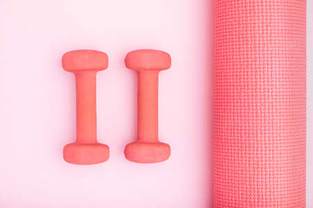 Pink exercise mats in center of light background with women's fitness yoga mat. Minimal artistic concept.の写真素材