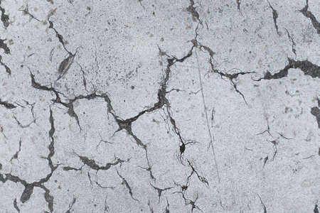 Cracks in old cement street road. Textured pattern background.の写真素材