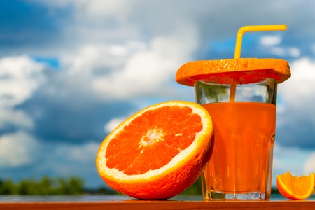 orange juice and orange against the sky close-upの写真素材