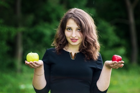 beautiful girl in a black dress holding apples in the forestの写真素材