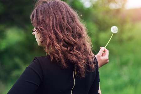 Beautiful girl standing with dandelion in handの写真素材