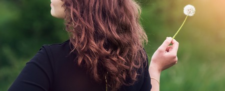 Beautiful girl standing with dandelion in handの写真素材