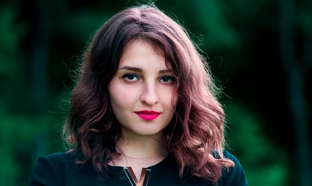 Beautiful girl with curly hair and red lipstick on the lipsの写真素材