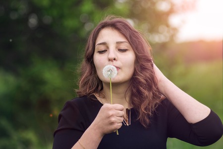 Beautiful girl standing with dandelion in handの写真素材