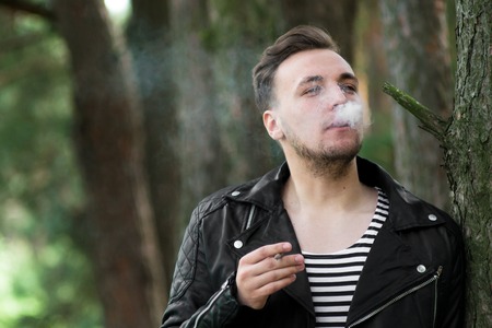 The guy in the leather jacket smoking in the woodsの写真素材
