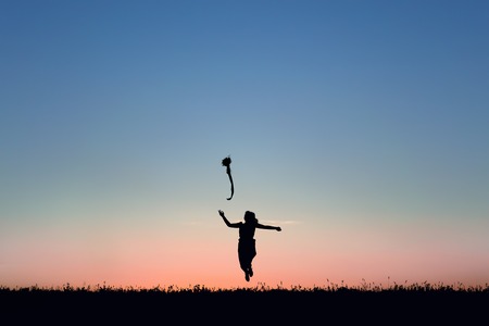Silhouette of a beautiful girl jumping over sunsetの写真素材