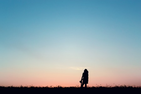 Silhouette of a beautiful girl jumping over sunsetの写真素材