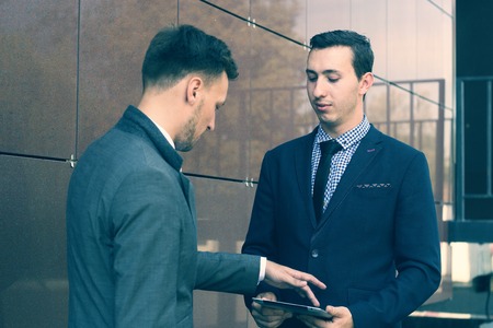 Two young managers talking and looking at a tabletの写真素材