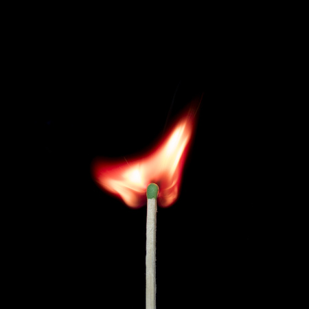 Burning match close-up on a black background.